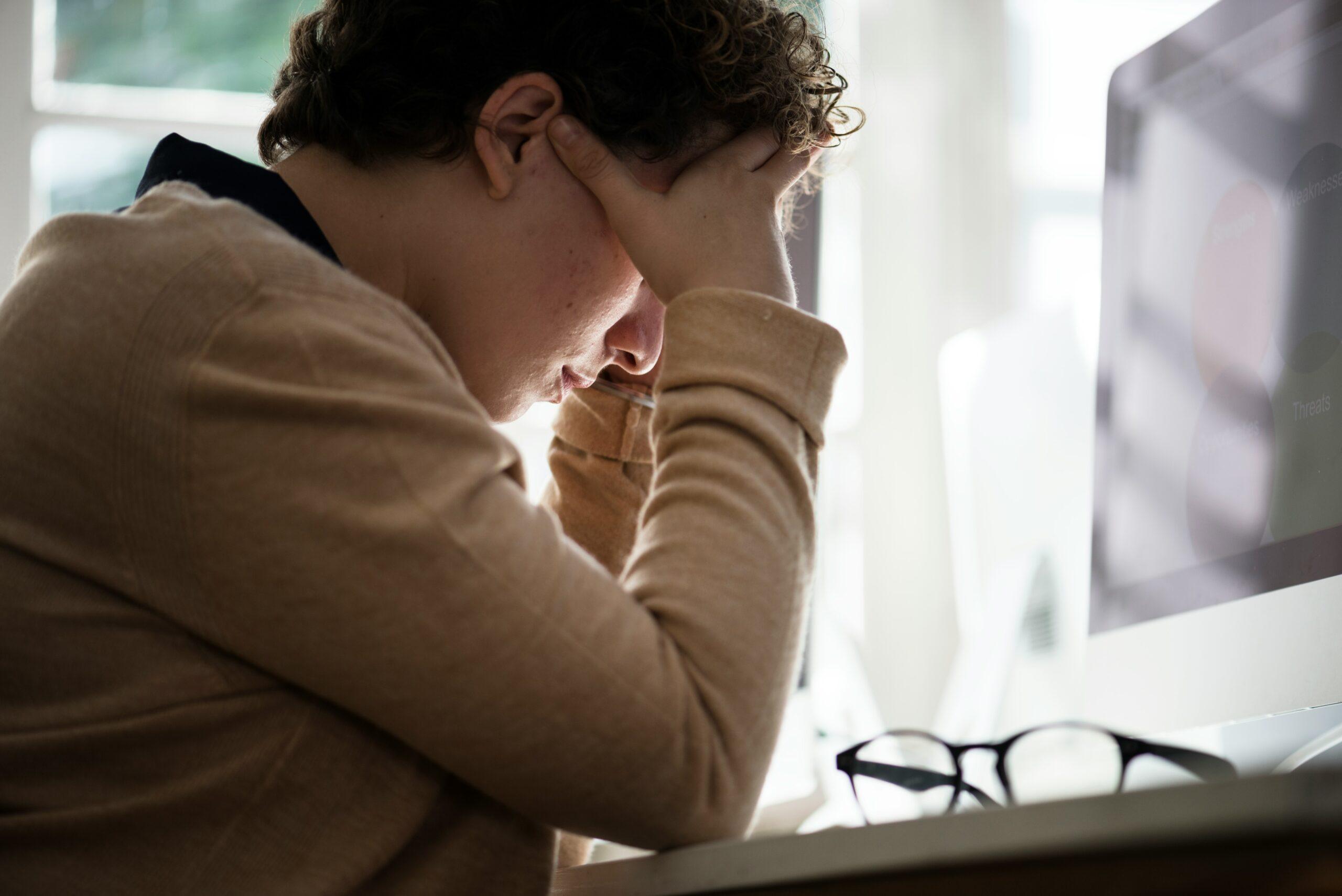 a man holding his head in frustration while looking at a computer monitor