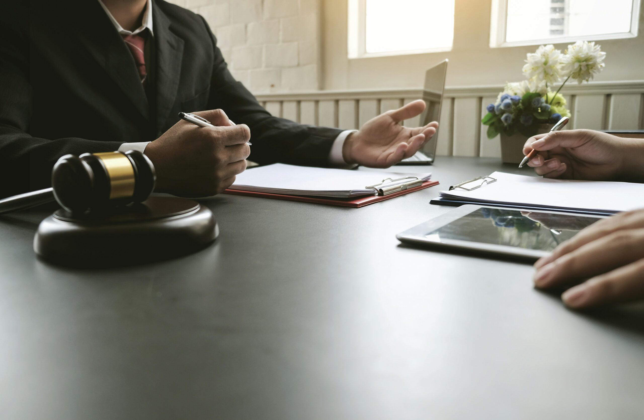 “Lawyer consulting with a client in an office, reviewing documents and explaining legal rights after reporting harassment.”