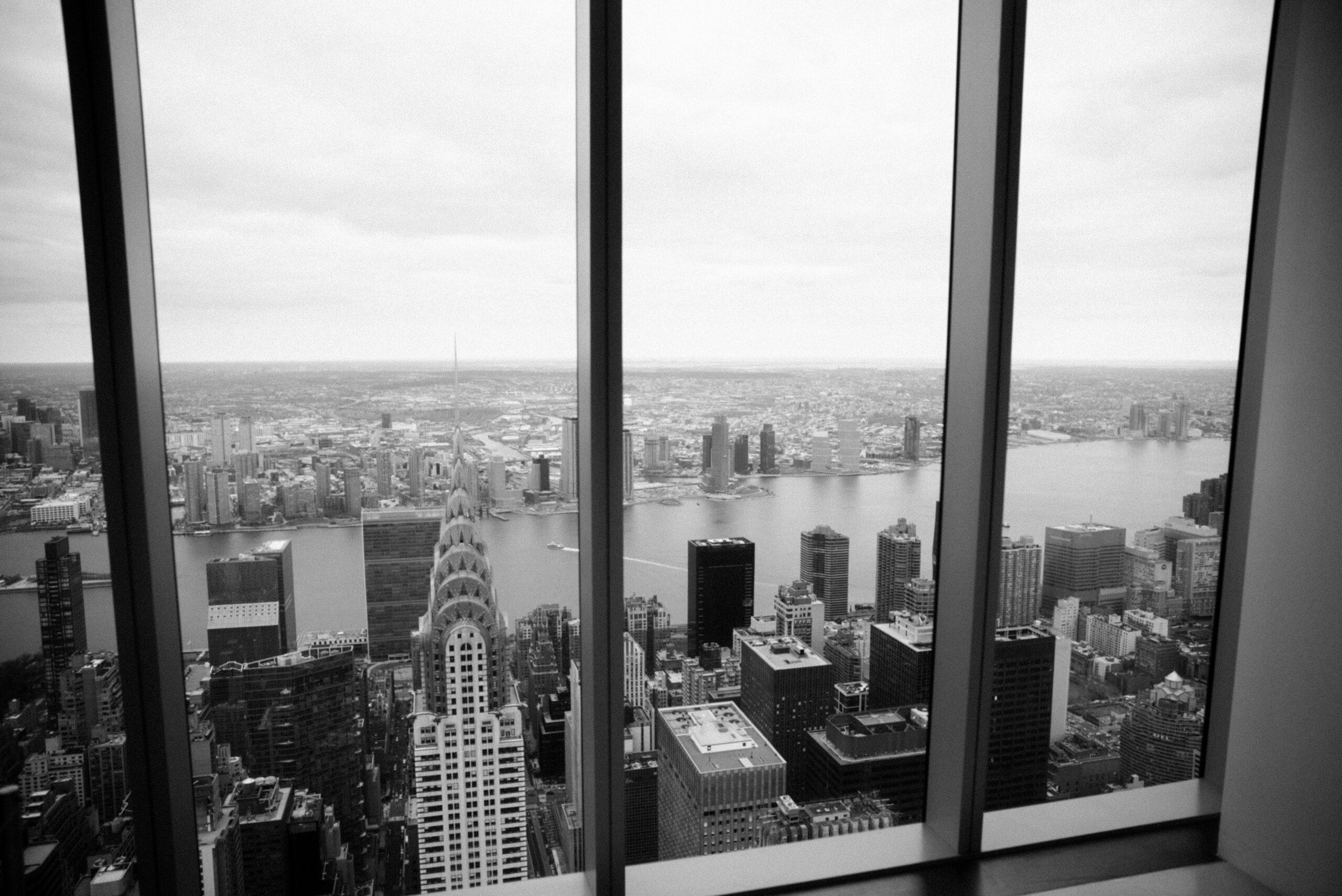 A view from an office building in Manhattan. You can see the Chrysler Building and the East River. the photos is black and white.